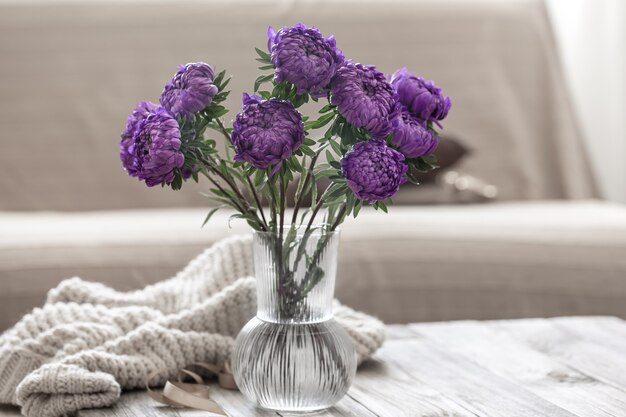 Un bouquet de chrysanthèmes bleus dans un vase en verre sur la table à l'intérieur de la pièce.