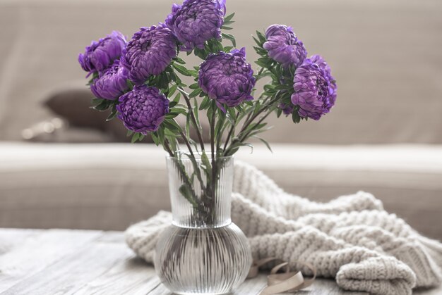 Un bouquet de chrysanthèmes bleus dans un vase en verre sur la table à l'intérieur de la pièce.