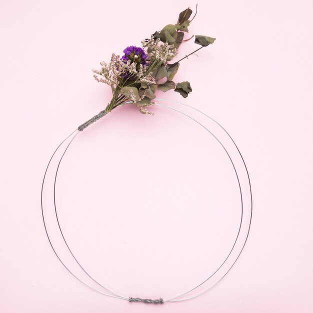 Bouquet de fleur noué sur un anneau de fil métallique pour cadre sur fond rose