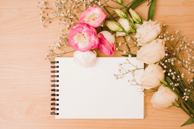 Bouquet de fleurs avec bloc-notes en spirale blanche sur fond en bois
