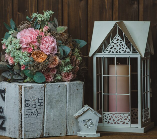 Bouquet de fleurs, bougie dans la cage et boîte en bois rustique