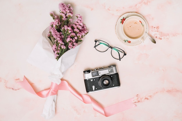 Photo gratuite bouquet de fleurs avec caméra et café sur la table