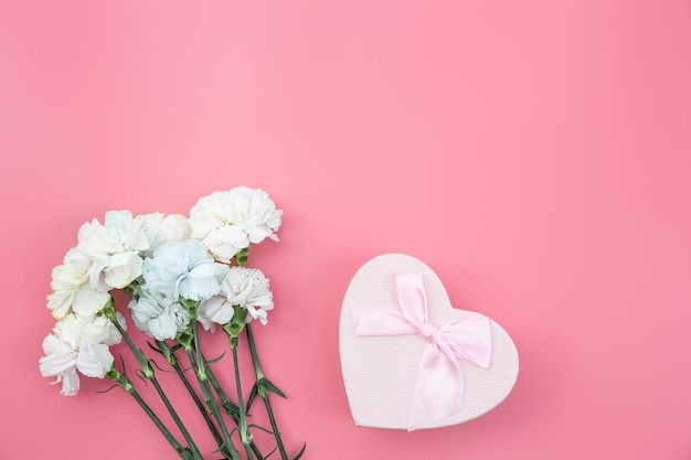 Bouquet de fleurs coffret cadeau en forme de coeur sur fond rose à plat