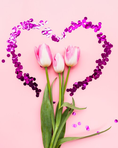 Bouquet de fleurs dans un cadre coeur sur fond rose