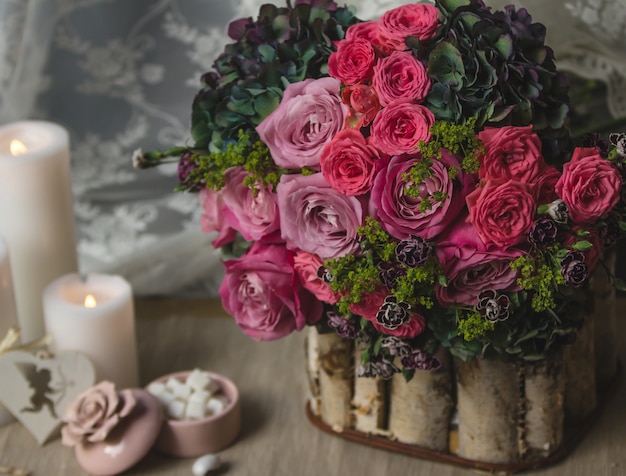 Photo gratuite bouquet de fleurs dans un support en bois avec des bonbons et des bougies