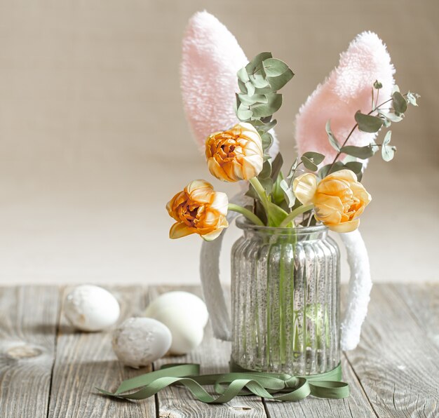 Un bouquet de fleurs dans un vase en verre avec des éléments décoratifs. Concept de vacances de Pâques.