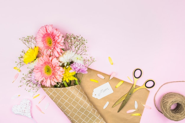 Bouquet de fleurs fraîches dans une enveloppe près d&#39;une étiquette avec un mot de maman et des ciseaux