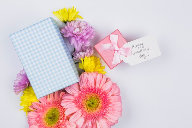 Bouquet de fleurs fraîches près de tag avec des mots et des boîtes à cadeaux