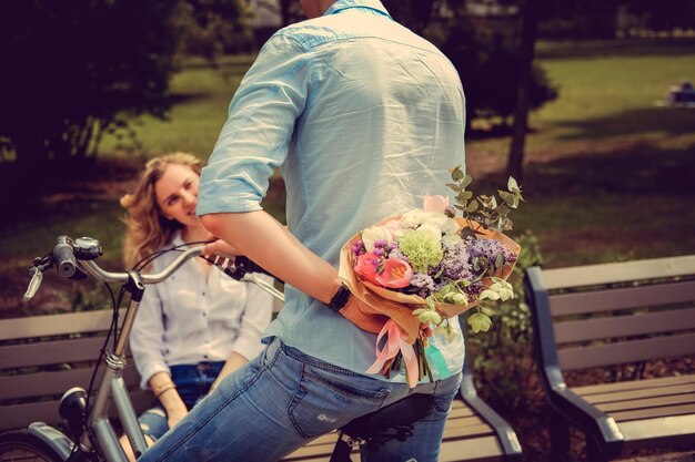 Bouquet de fleurs surprise d'un homme décontracté sur un vélo à une jolie femme blonde.