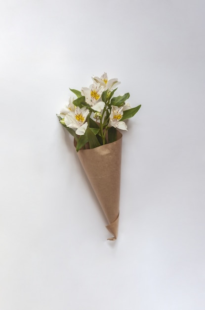 Photo gratuite bouquet de lys péruviens blancs enveloppés de papier brun sur fond blanc