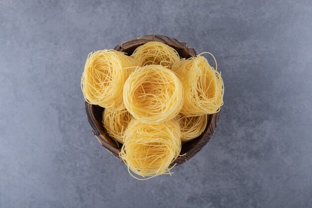 Bouquet de nids de pâtes crues dans un seau en bois.