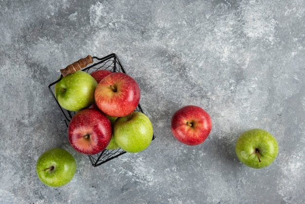 Bouquet de pommes vertes et rouges fraîches placées dans un panier en métal.