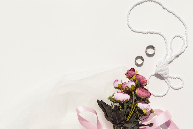 Bouquet de roses à côté d'articles de mariage avec espace de copie