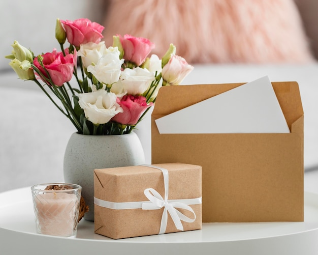 Bouquet de roses dans un vase à côté de cadeau emballé et enveloppe