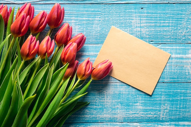 Un bouquet de tulipes et un morceau de papier pour le texte sur un fond en bois