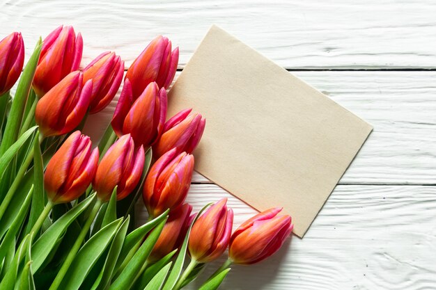 Un bouquet de tulipes et un morceau de papier pour le texte sur un fond en bois