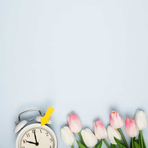 Photo gratuite bouquet de tulipes à plat à côté de l'horloge