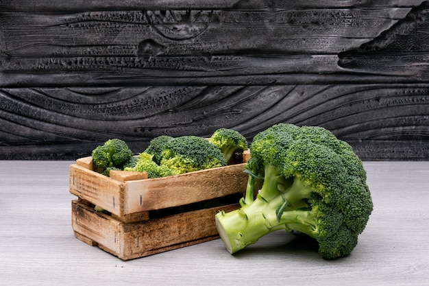 Bouquets de brocoli dans une boîte en bois près du brocoli frais entier