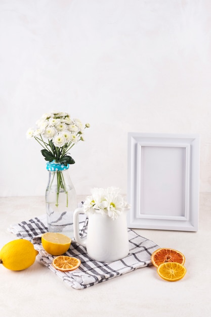 Bouquets de fleurs fraîches dans un vase près des fruits et cadre photo