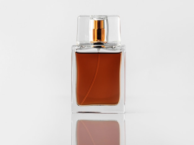 Une bouteille brune vue de face avec parfum et avec bouchon d'or sur le bureau blanc