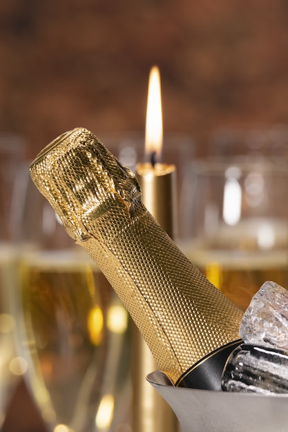 Une bouteille de champagne avec des glaçons et une bougie allumée floue à l'arrière. concept de célébration.