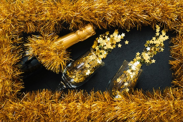 Bouteille de champagne avec des lunettes dans un cadre de guirlandes