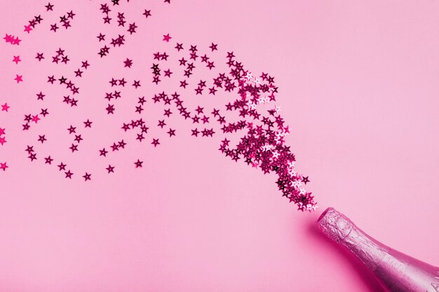 Bouteille de champagne rose avec des paillettes en forme d'étoile