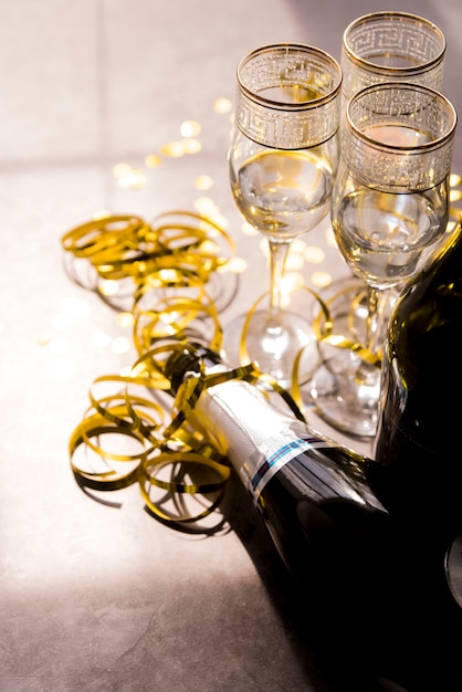 Bouteille de champagne vide et verre avec des banderoles dorées à la fête