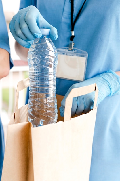 Photo gratuite bouteille d'eau ajoutée au sac de don