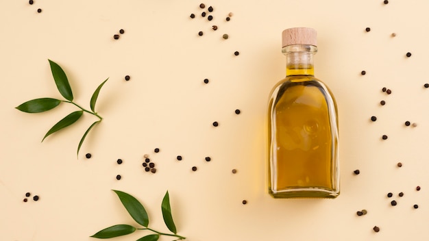 Bouteille d'huile d'olive avec des feuilles à côté de la table