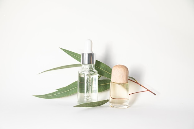 Une bouteille d'huiles essentielles et de feuilles d'eucalyptus sur fond blanc Concept de soins de la peau et du corps