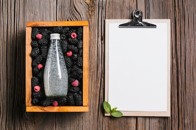 Bouteille de jus de mûre sur une boîte en bois avec le presse-papier