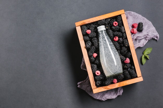 Photo gratuite bouteille de jus de mûre sur une boîte en bois