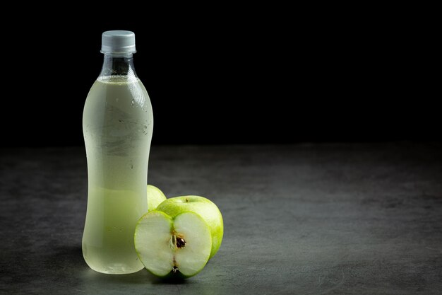 Une bouteille de jus sain de pomme verte mis à côté de pommes vertes fraîches