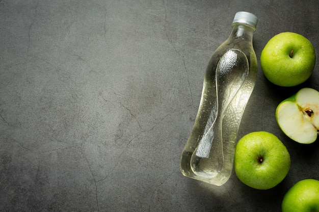 Une bouteille de jus sain de pomme verte mis à côté de pommes vertes fraîches