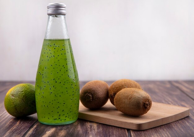 Bouteille de jus de vue avant avec mandarine verte et kiwi sur une planche à découper