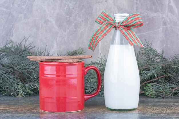 Une bouteille de lait avec arc et verre sur marbre