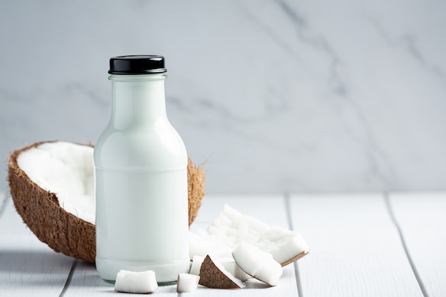 Bouteille de lait de coco mis sur fond de bois blanc