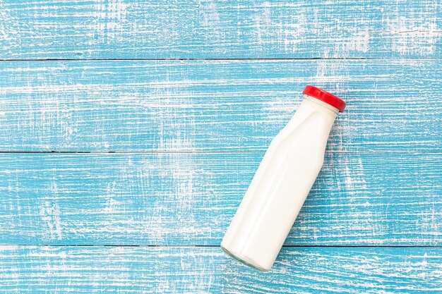 Bouteille de lait sur un fond bleu en bois à plat