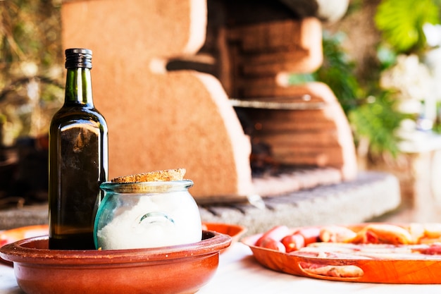 Bouteille et pot de sel avec assortiment de viande sur la table près du barbecue