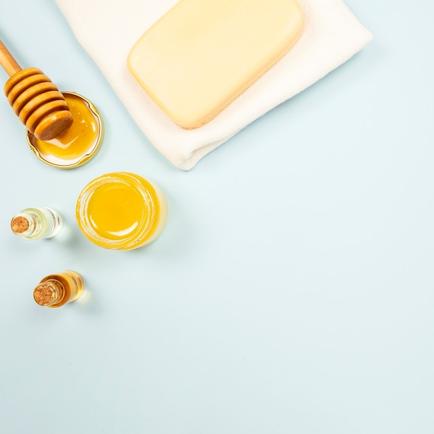 Une bouteille de savon et d’huile essentielle avec du miel sur un fond uni