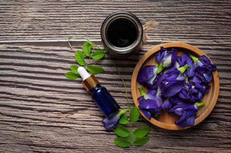 Photo gratuit bouteille de sérum d'huile de fleur de pois papillon mis sur fond de bois