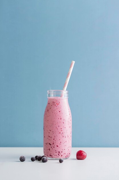 Bouteille de smoothie rose vue de face avec paille et copie-espace