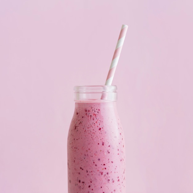 Bouteille de smoothie rose vue de face avec de la paille