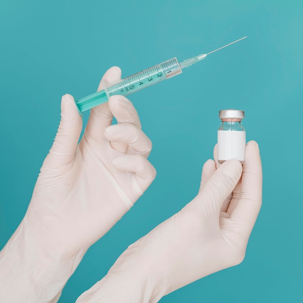 Photo gratuite bouteille de vaccin et seringue tenue à la main avec des gants