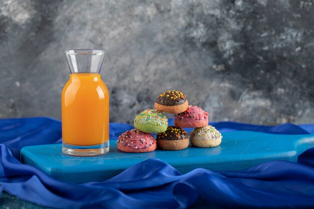 Une bouteille en verre de jus avec des beignets colorés.