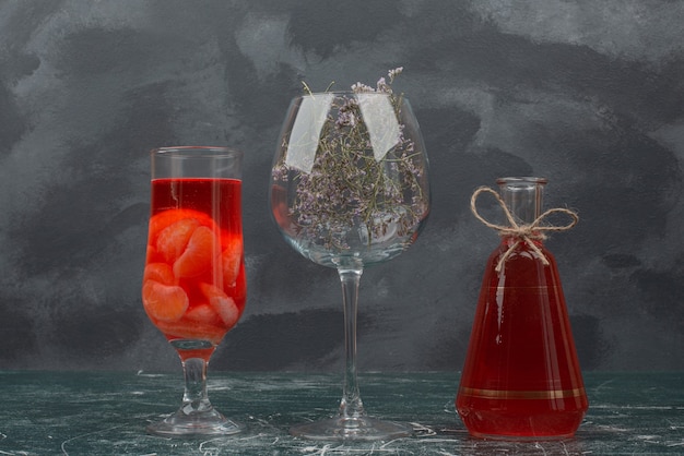 Bouteille et verre avec jus et verre avec fleur.