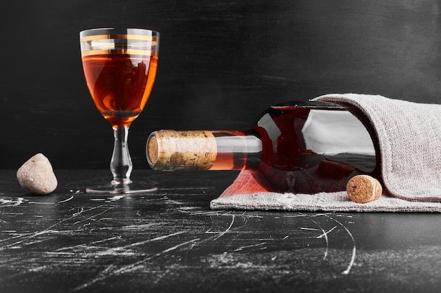 Une bouteille et un verre de vin rosé.