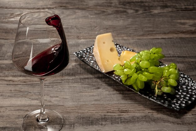 Une bouteille et un verre de vin rouge avec des fruits sur une surface en bois patiné