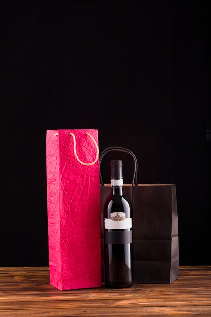 Bouteille de vin noir avec un beau sac en papier sur une table en bois